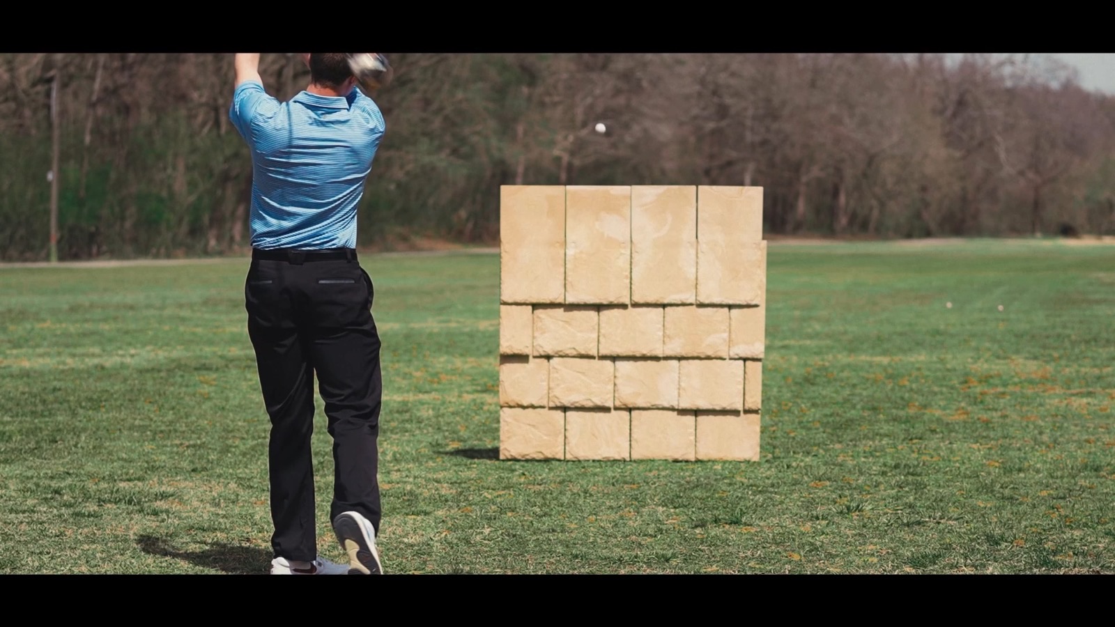 Golf club driving a ball at a Brava composite tile wall to demonstrate Class 4 impact resistance
